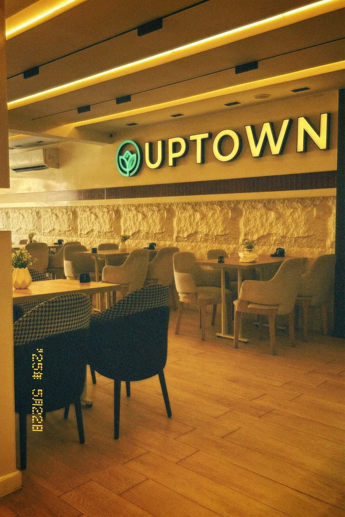 صالة أب تاون من بره: لافتة UPTOWN منوّرة، كراسي هاوندزتوث وأرضية خشب